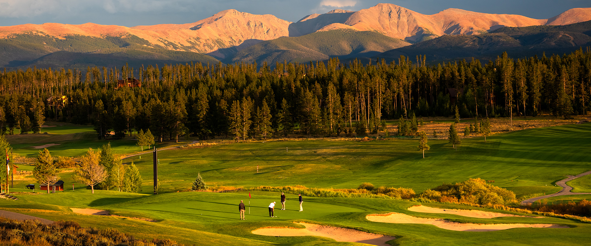 A group of golfers putting on a green at Pole Creek Golf Club during a captivating sunset.
