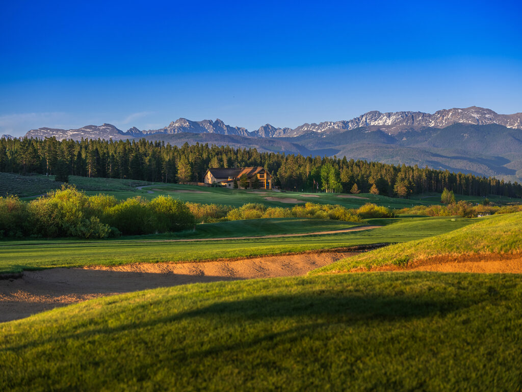 Pole Creek Golf Course stretches towards a large, rustic-style clubhouse nestled among dense forests