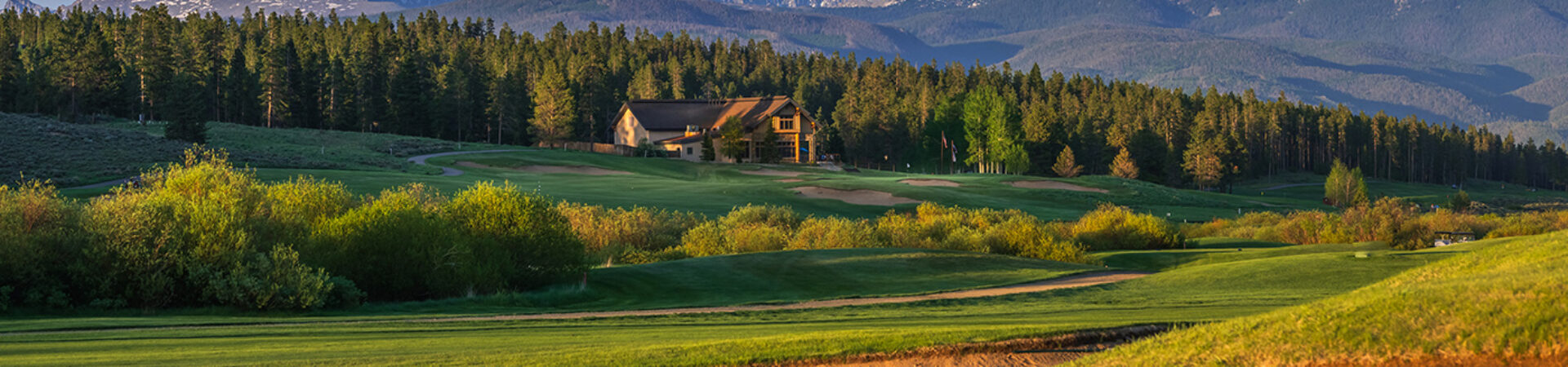 Pole Creek Golf Course stretches towards a large, rustic-style clubhouse nestled among dense forests